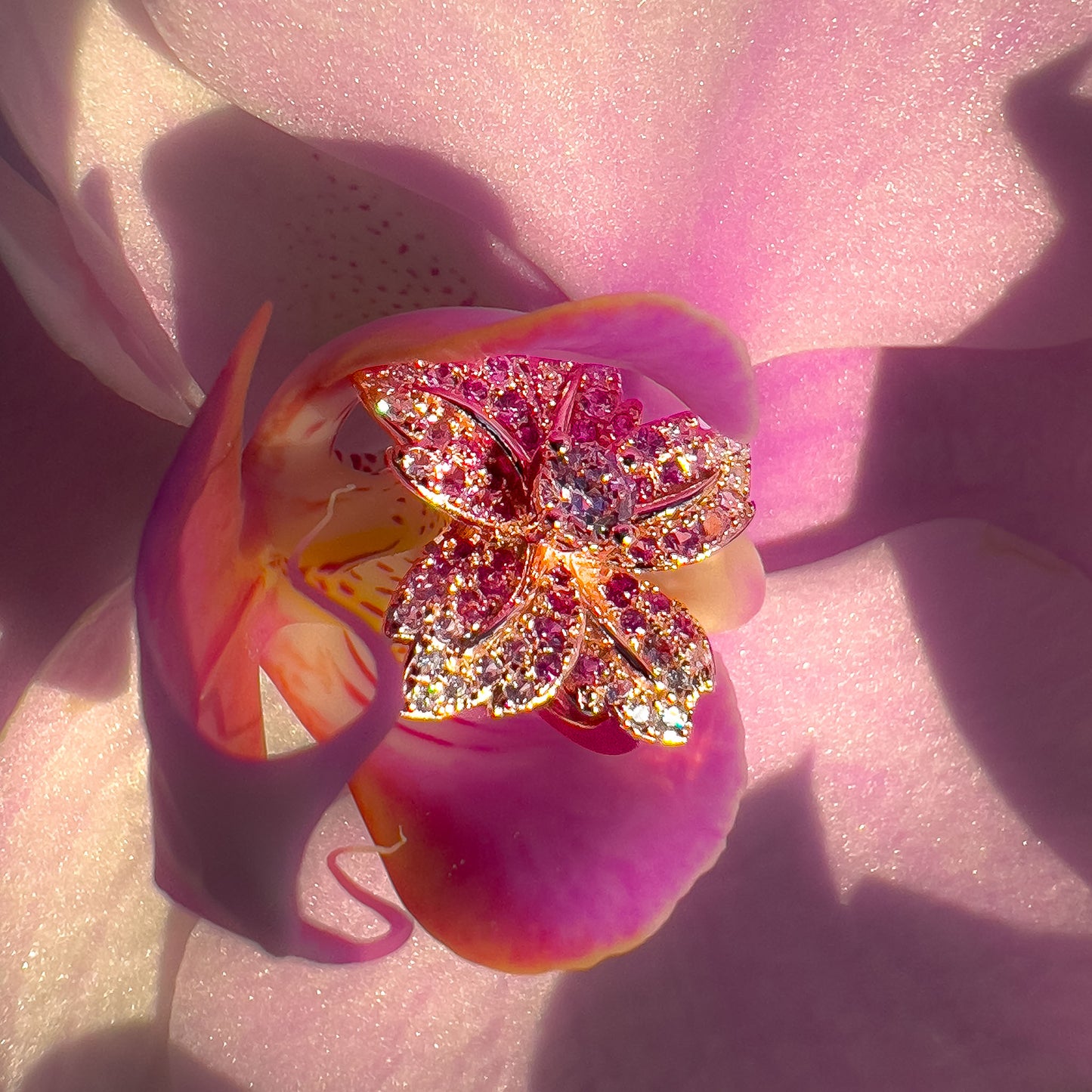 Lotusglød Blomst Øredobber i sølv med rosa cubic zirkonia som midtpunkt, omgitt av gullbelagte kronblader dekorert med rosa safirer, rubiner og hvite cubic zirkonia.