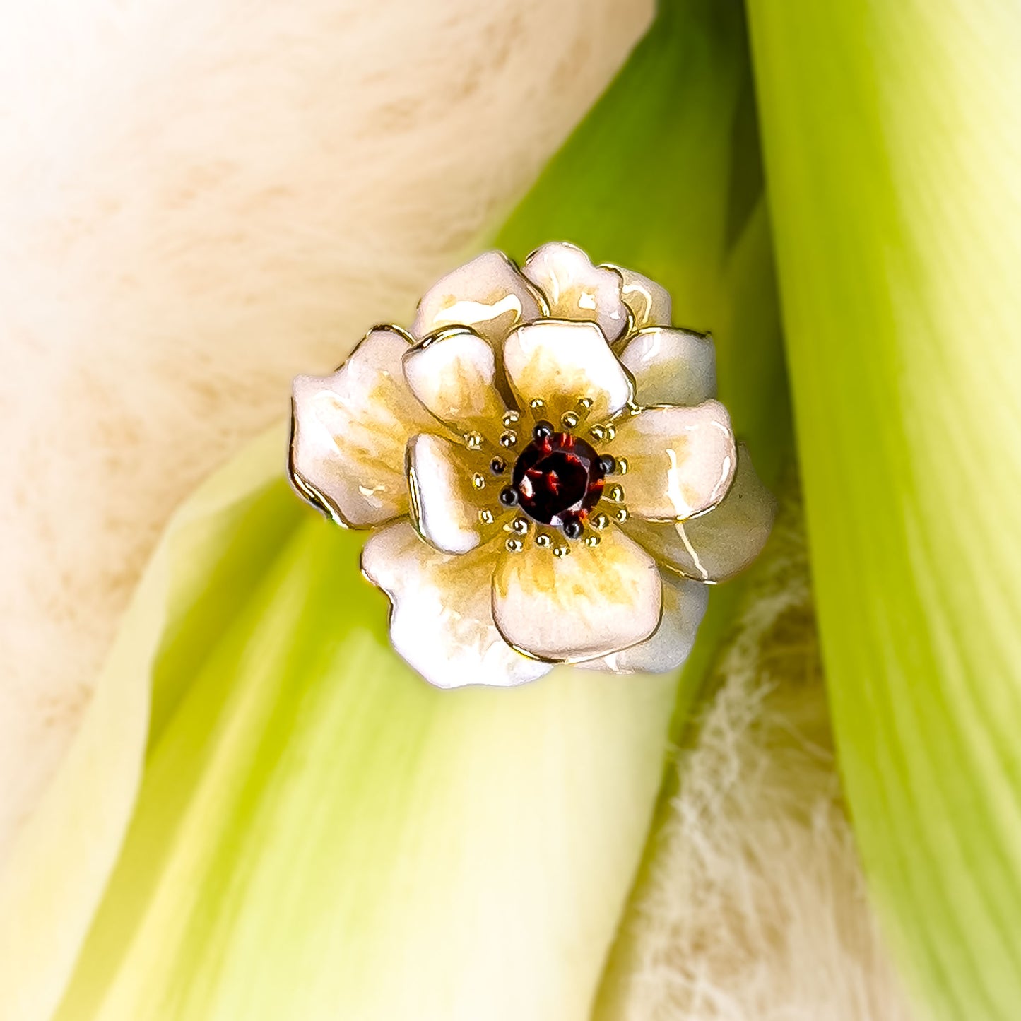 Sølv anheng i blomst forme med granat cubic zirkonia i midten av Hvit Magnolia Anheng, omgitt av delikate håndmalte emaljedetaljer. Et sølv smykke i gullbelagt sølv med emalke og stener.