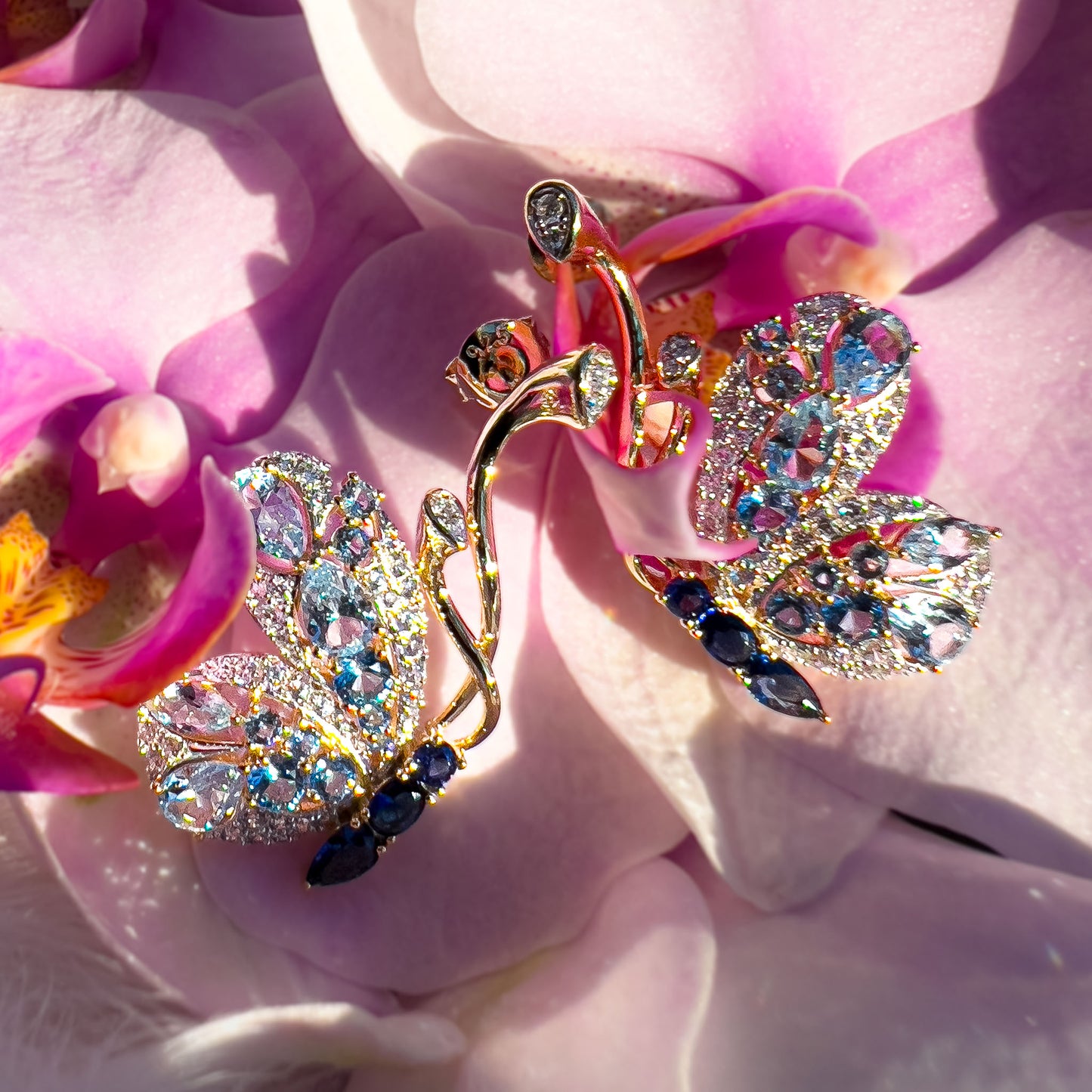 Gullbelagte sølv øredobber i sommerfugl form i ekte sterling sølv med edelstener. Detaljbilde av dette slølv smykke med gul forgylling, blå spineller,  glass og cubic zirkonia, som fremhever sommerfuglens delikate vinger.